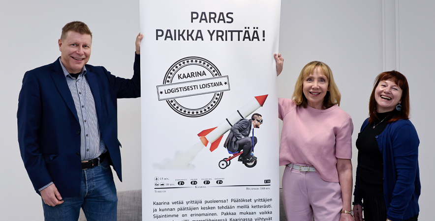 Kari Saarinen, Maria Haapanen ja Ritva Lindström hymyilevät Kaarinan kehityksen rollupin ympärillä. Rollupissa lukee "Paras paikka yrittää".